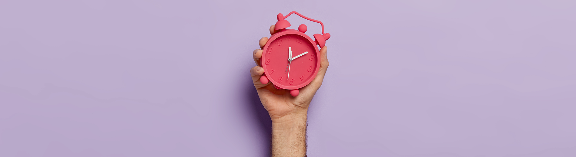 hand with a pink alarm clock 